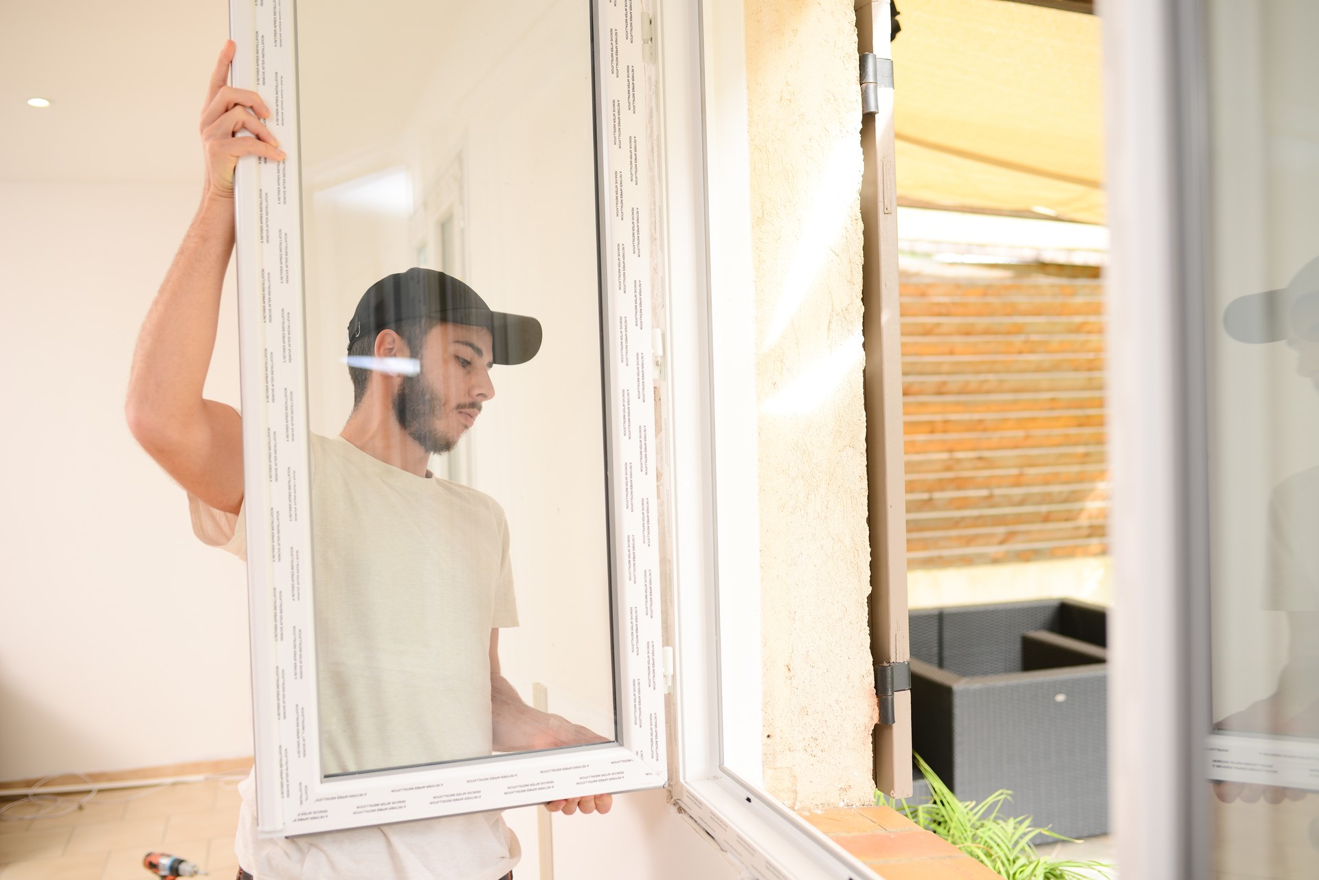 gutaussehender junger professioneller Mann, der ein neues Fenster im Kundenhaus installiert und ersetzt, um die Isolierung der Energieeinsparung zu verbessern